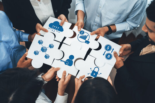 Diverse corporate officer workers collaborate in office, connecting puzzle pieces to represent partnership and teamwork. Unity and synergy in business concept by merging jigsaw puzzle. Concord Amity - Powered by Adobe
