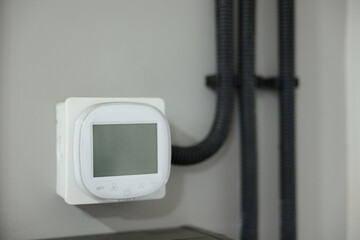 Modern digital thermostat mounted on a wall in a stylish room, ensuring climate control for comfort