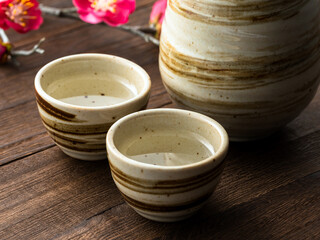 陶器の酒器と梅の花の和風テーブルイメージ
