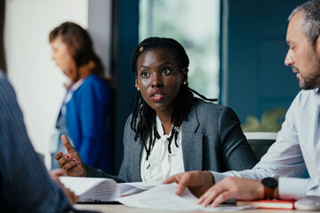 Black Female Manager Providing Feedback to Junior Employee in Multicultural Office