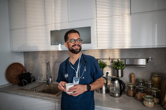 Smiling male doctor taking coffee break in kitchen