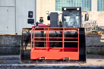 Black and red telehandler versatile agricultural and construction vehicle with attachment large bucket and scoop heavy equipment used in construction and agriculture, front view