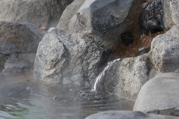 Hot steaming water flowing into Japanese outdoor public foot spa