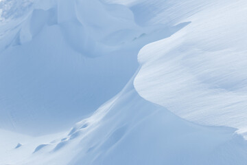 Curved edge of pale blue snowdrift and shadow in winter landscape