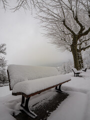 Empty snow covered park bench symbolizing waiting, solitude, or rest