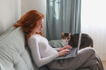 Young woman working on a laptop at home with a cat nearby ideal for remote work concepts home office lifestyle and productivity themes