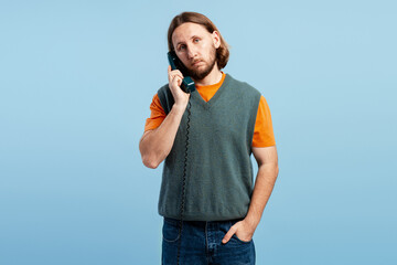 Man talking on a retro corded telephone, showing a bored and awkward expression