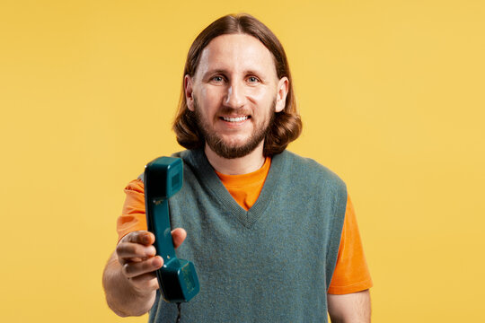 Smiling man offering a vintage telephone receiver, symbolizing connection and communication
