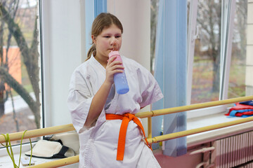 Sportive young girl wearing kimono doing exercises in large sports hall