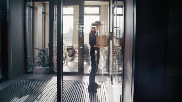Male courier delivering a parcel walking through a contemporary residential building lobby