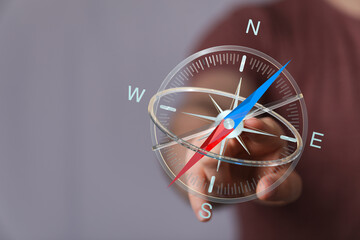 Hand pointing towards a digital compass, representing direction, navigation, and guidance in...
