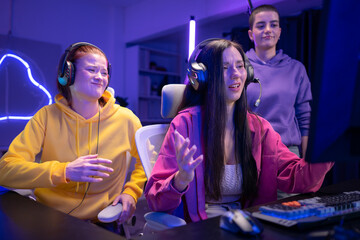 Group of woman play online game and celebrating a gaming victory in a neon-lit room