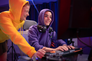 Young woman focused gamer in a hoodie playing with a controller at a desk © Wosunan