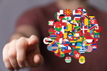 A person's hand pointing toward a cluster of international flags, representing global connections and unity. The image conveys concepts such as