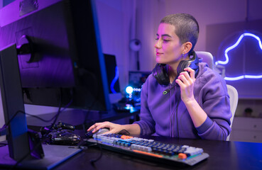A focused gamer sits at a desk and types on a mechanical keyboard in a neon-lit gaming setup