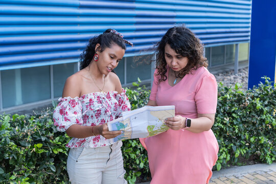 Two women friends navigating journey with paper map