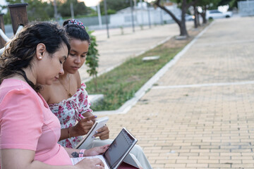 Women collaborating on laptop and notebook outdoors