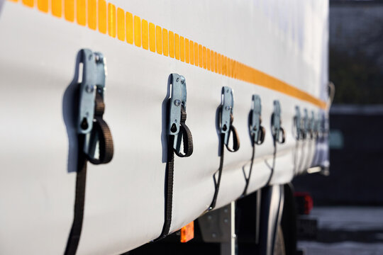 Truck or trailer curtain side system tensioning buckles and straps to secure side curtain of commercial vehicle, ensuring cargo is protected and curtain remains taut during transit.