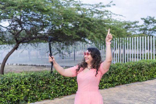 Woman vlogging outdoors pointing up with action camera