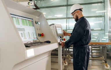 Looking at display of machine, operator is working. Warehouse worker in an industrial environment...