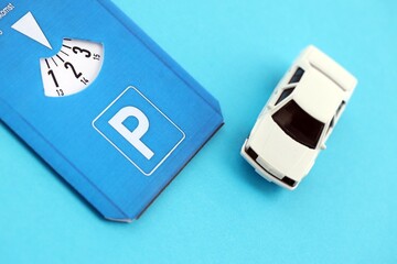 Parking disc for windshield and white toy car. Limited time parking system in european countries. Concept of parking time count in busy parking lots