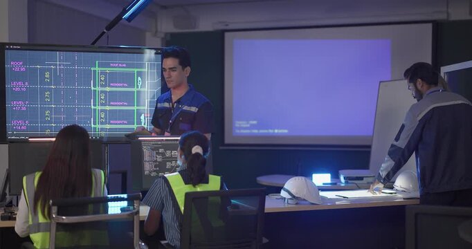 Engineers in high visibility vests collaborate in control room, reviewing digital site plans and dashboards during an operations and safety discussion. Coordination, monitoring, and incident readiness