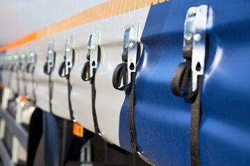 Truck or trailer curtain side system tensioning buckles and straps to secure side curtain of commercial vehicle, ensuring cargo is protected and curtain remains taut during transit.