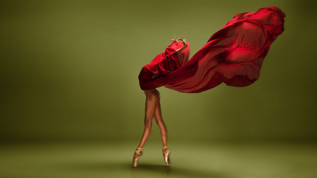 Ballet dancer in red fabric sweep on olive green background in motion. Concept of advertising motion assets, dance storytelling, modern artistic branding.