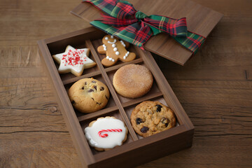Overhead view of a rustic wooden box filled with a variety of delicious homemade christmas cookies tied with a festive plaid ribbon