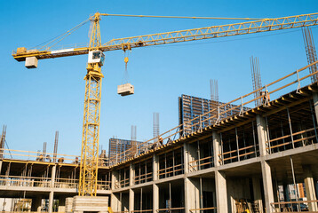 A yellow construction crane lifting concrete block at a building construction site scene