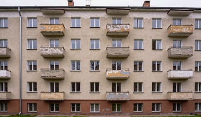 Obraz premium Old apartment building with peeling paint and empty balconies in a quiet neighborhood
