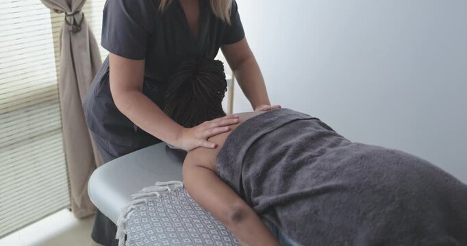 Female chiropractor therapist doing back massage to a senior woman patient inside her studio - Healthcare, wellness and healthy lifestyle concept