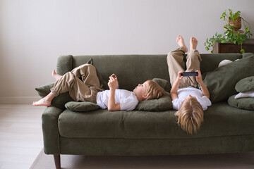 kids boys twins using smartphones lying on the couch