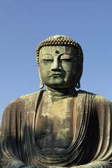 Great Buddha of Kamakura against a clear blue sky, capturing the serene expression of the iconic Daibutsu statue
