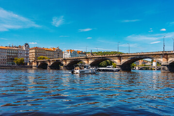 Palacky Bridge. Boats cruising under historic stone bridge with buildings.