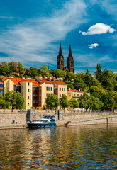 Vysehrad Basilica and colorful buildings along Vltava embankment.