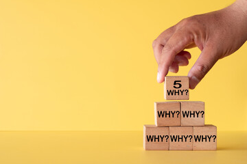 Hand stacking wooden blocks with text 5 WHY? representing Root Cause Analysis and Problem Solving Technique used in Lean Six Sigma and Business Strategy.