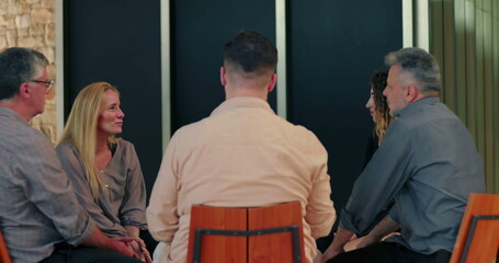 Support group gathered in circle as woman opens up, participants listening attentively in moment of...