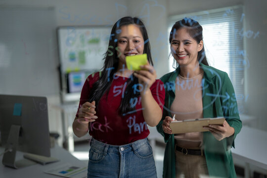 Businesswomen collaborating on glass board planning new strategy