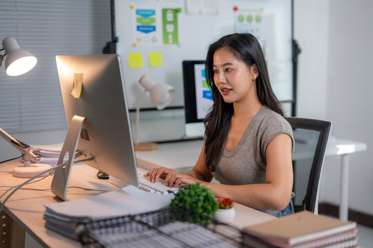 Asian businesswoman working late on computer in office - Powered by Adobe