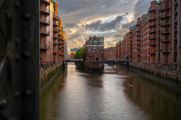 A refined angle of speicherstadt in hamburg showing canal routes and waterway contrast beside brick architecture within the urban historic district illuminated by soft evening light perspective