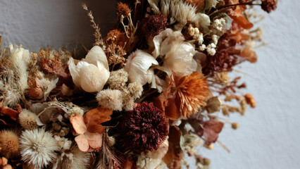 A rustic close-up of a dried flower wreath, featuring various preserved botanicals in warm autumn and neutral tones, perfect for natural decor.