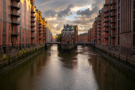 View of speicherstadt in hamburg focused on canal depth and waterway balance surrounding brick architecture that defines the urban historic district under gentle evening light perspect