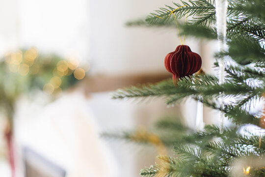 Stylish paper baubles on Christmas tree branches close up. Modern ornaments on decorated xmas tree with lights. Winter holiday banner, atmospheric christmas time. Merry Christmas! - Powered by Adobe