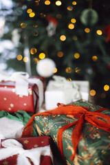 Stylish Christmas gift boxes on background of decorated xmas tree with golden lights. Merry Christmas and Happy Holidays! Atmospheric winter time. Wrapped Christmas presents banner