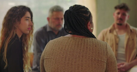 Support group listening attentively as woman shares her story, seated in healing circle during...
