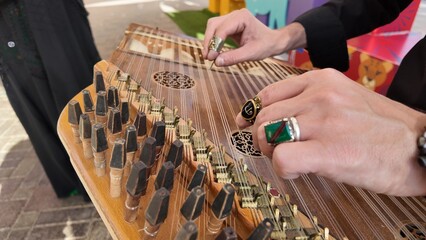 man playing qanun, traditional turkish instrument, kanun, turkish man performing wooden string instrument in Al Ain Zoo Celebration of Independence Day of the UAE.2 December 2025 
