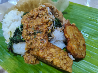 Nasi pecel and sego pecel are typical Javanese Indonesian rice dishes served with pecel sauce, vegetables and others.	