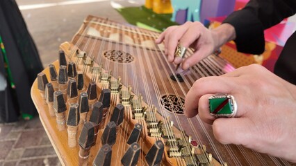 man playing qanun, traditional turkish instrument, kanun, turkish man performing wooden string instrument in Al Ain Zoo Celebration of Independence Day of the UAE.2 December 2025 