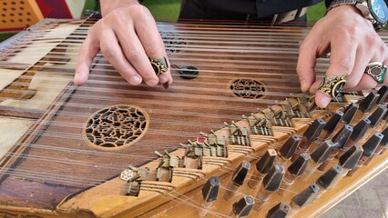 man playing qanun, traditional turkish instrument, kanun, turkish man performing wooden string instrument in Al Ain Zoo Celebration of Independence Day of the UAE.2 December 2025 